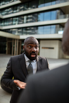 Businessman expressing shock during conversation outside office building