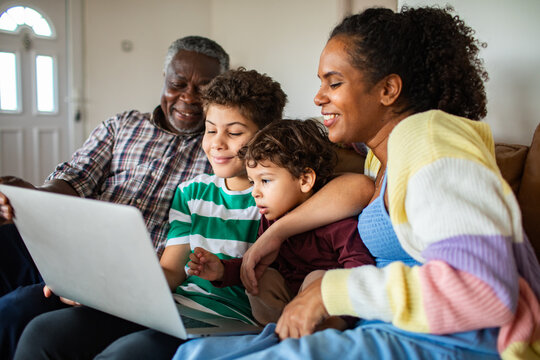 Multigenerational family watching laptop on sofa at home