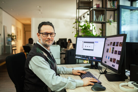 Middle-aged professional working on dual monitors in modern office