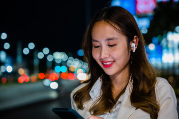 Young woman using modern smartphone in night city