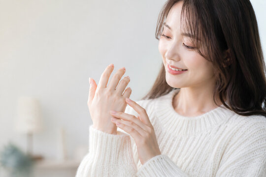 保湿された自分の手を見つめて微笑む女性