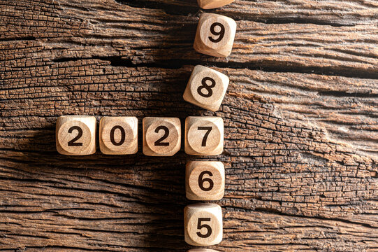 Wooden blocks forming numbers year 2026 to year 2027 on rustic wooden table surface