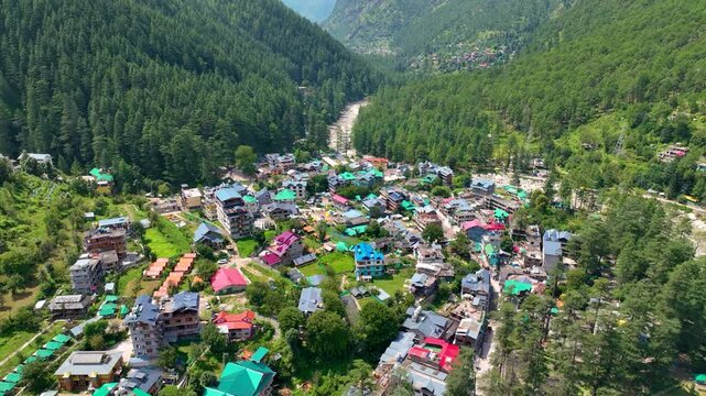 High angle drone glide across rural mountain homes in Tosh nestled in dense Himalayan cedar forests near the popular Kheerganga trekking route in Kullu District.