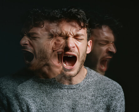 Man portrait of a distressed male person screaming in anger and rage with motion blur effect against dark background