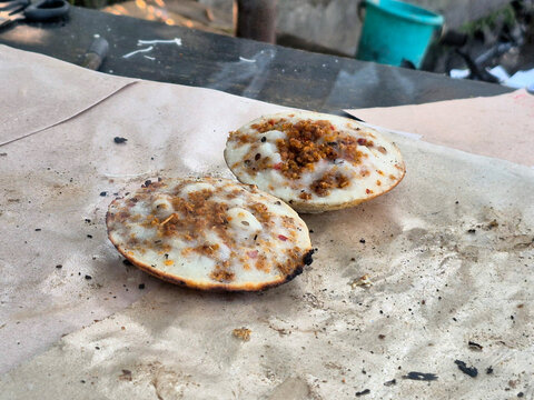 Two Freshly Prepared Traditional Indonesian Surabi Rice Flour Pancakes Topped with Savory Fermented Oncom Served on a Rustic Wooden Table