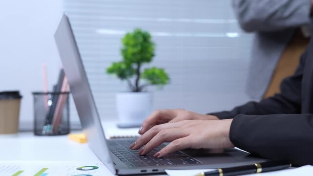  Close-up of Asian businesswoman using mobile phone, texting and cheating on her smartphone while outside office.