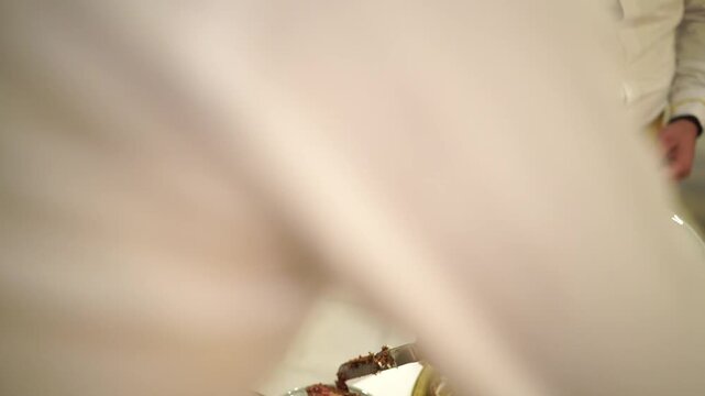 Waiters serving slices of two-tier wedding cake on gold tray at reception