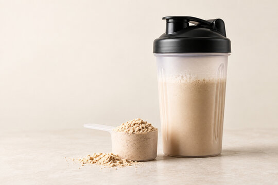 Protein shaker with a scoop of powder on a cream background