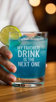 Cool blue cocktail in glass with lime garnish, held by hands, implying anticipation of another beverage.