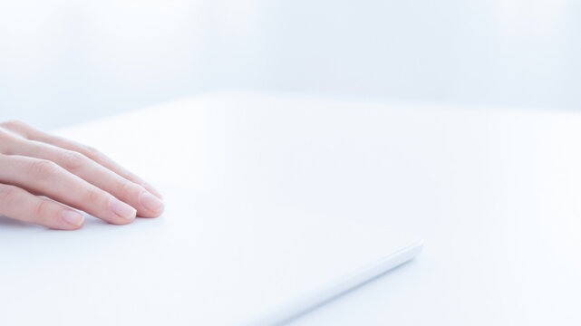 Hand resting beside slim white device on clean desk suggests modern digital workspace and quiet focus at home or office