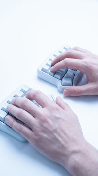 Hands typing on ergonomic keyboard for digital work and office productivity, viewed from above with clean background and focus on technology