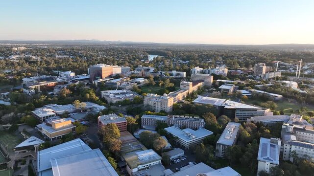 Slow tracking aerial shot over the University of Queensland campus, heritage sandstone and modern faculty buildings set among mature trees, golden hour, St Lucia, Brisbane, Queensland