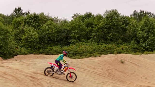 Motocross rider in a sand pit preparing to ride and do tricks over a big jump