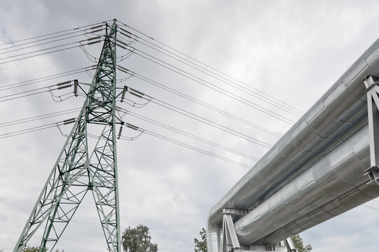 a pipeline and a power transmission tower against a gray sky