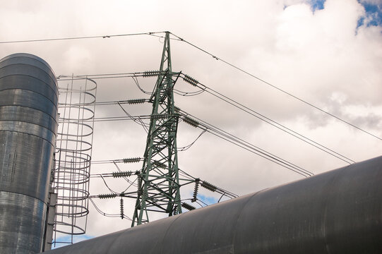 a pipeline and a power transmission tower against a gray sky