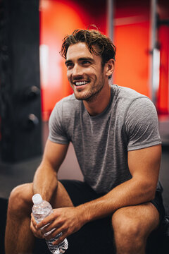 Athletic Man Resting and Holding Water Bottle During Gym Workout Session