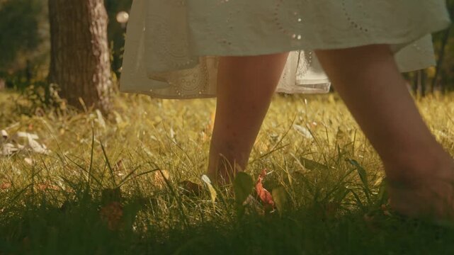 The feet of a grown woman are walking on the grass. Walking barefoot on green grass. Unity with nature.