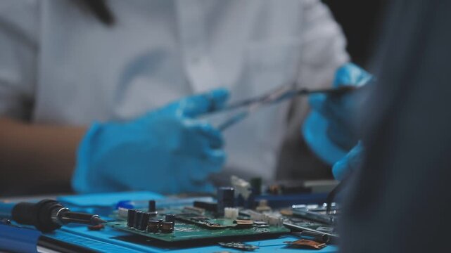 Technician using soldering iron on electronic circuit board for hardware repair, engineering diagnostics, manufacturing maintenance