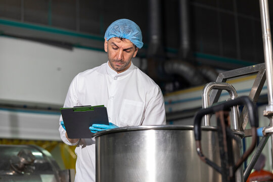 Industry inspector QC worker checking machine operation for safety and hygienic standard in food and drink factory.