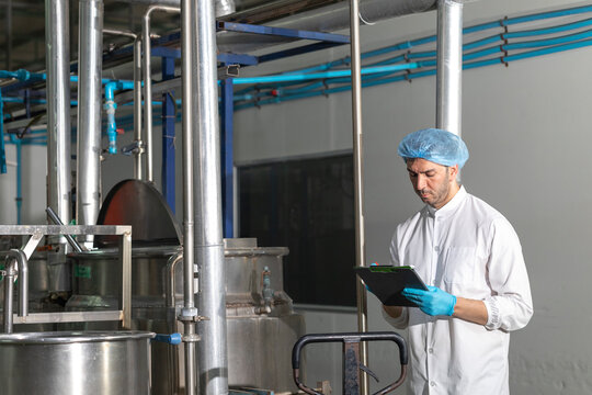 Industry inspector QC worker checking machine operation for safety and hygienic standard in food and drink factory.
