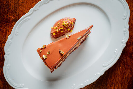 Delightful chocolate cake slice with creamy frosting and golden toppings on a decorative plate