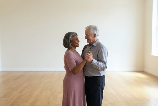 Multiracial senior couple slow dancing in an empty community hall