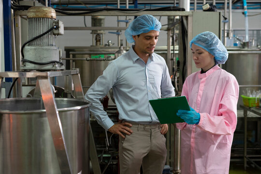 Food scientist man and woman worker inspecting work at food production factory plant.
