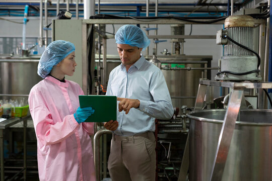 Food scientist man and woman worker inspecting work at food production factory plant.