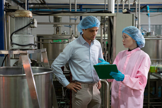 Food scientist man and woman worker inspecting work at food production factory plant.