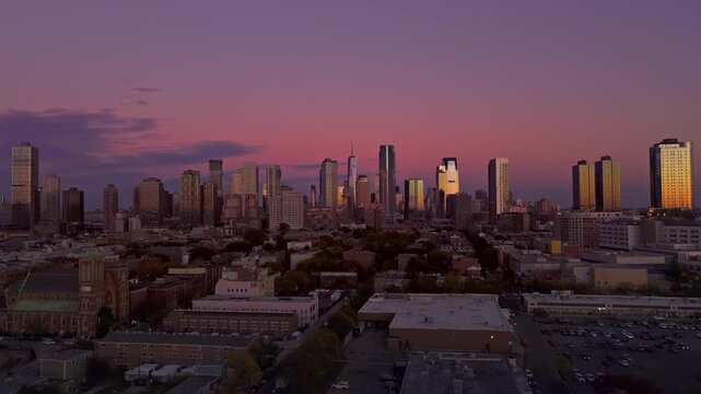 Aerial push in of Jersey City and Manhattan skylines at purple twilight