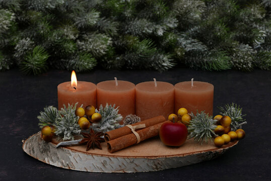 Rustic Advent arrangement with four candles on a wooden tray; one candle is lit for the first Sunday of Advent.