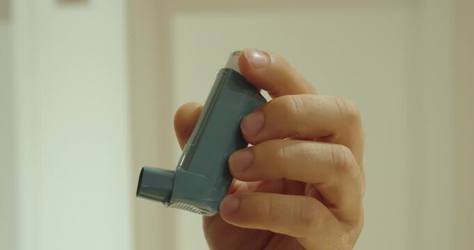 Close-up of a hand holding an asthma inhaler.