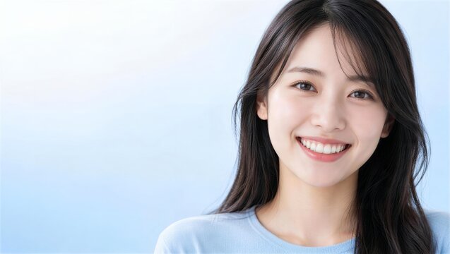水色のグラデーション背景で歯を見せて笑うロングヘアの女性