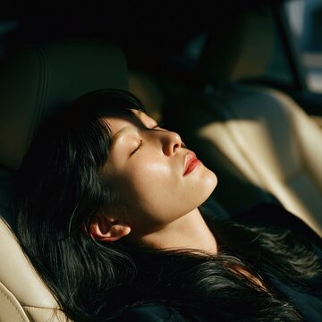 A woman sleeping in a modern car interior with the sunlight on her face, it is travel lifestyle visual emphasizing comfort and relaxation.
