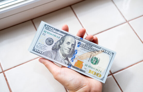 Hand holding US dollar banknotes, illustrating wealth, cash payments, financial transactions, corruption, bribery and money laundering