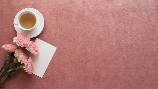 Mothers Day carnations and teacup on dark background with copy space
