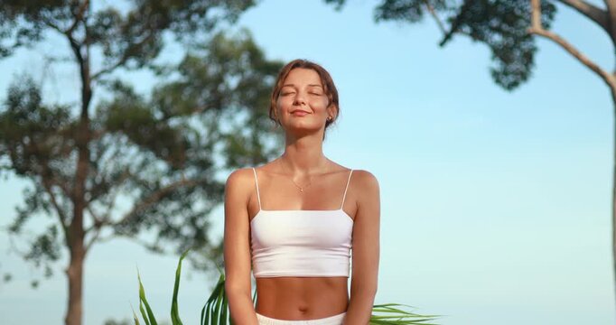 Smiling Woman Meditates Outdoors Under Blue Sky In Tropical Nature