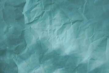 Obraz premium Crumpled light blue turquoise paper texture with soft light reflection, ideal as an abstract backdrop or graphic element for design projects.