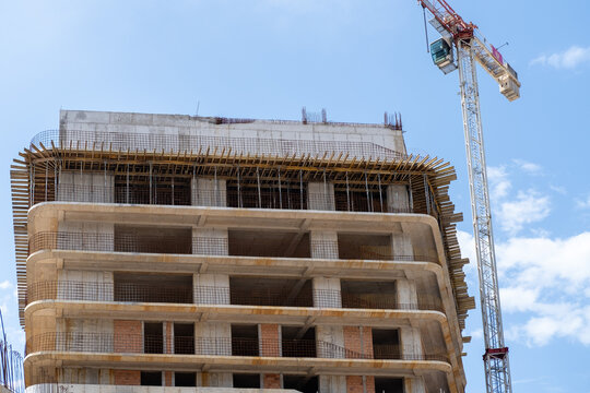 Residential real estate construction site with unfinished concrete buildings and a tower crane. Modern urban development and property construction concept.