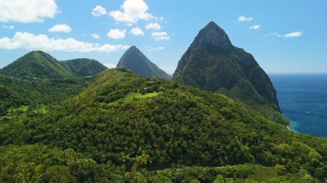 Twin volcanic Pitons peaks rise above lush rainforest hills viewed from Tet Paul Nature Trail overlooking Caribbean coastline Saint Lucia
