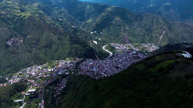 Wide Aerial View of Ecuador Mountain Town in Deep Valley, River, Green Slopes, Dense Buildings and Scenic Andean Travel Landscape