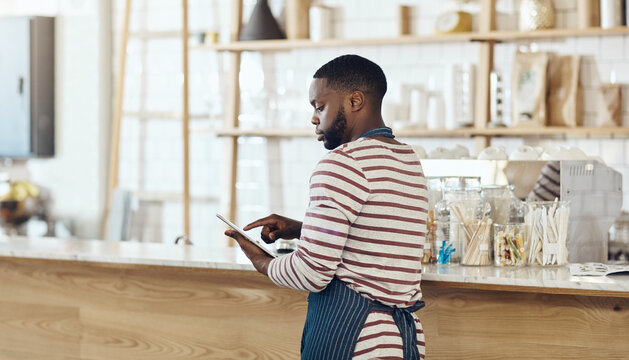 Hospitality, browse or black man in cafe with tablet, website check or delivery track on bistro app. Review, reading or barista in coffee shop with tech, online order or menu update on digital site
