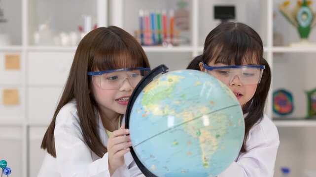 Elementary School Girls in Lab Coats Studying World Globe