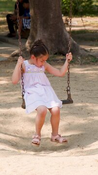Young Asian Girl in Pink Dress Playing on Swing at Lumpini Park