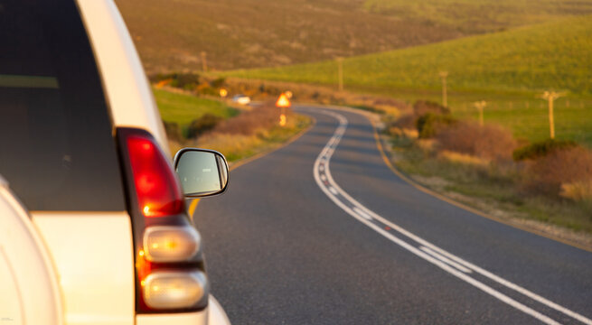 SUV and winding asphalt road, Stanford , South Africa at sunset