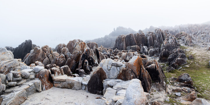 moody landscape of rock formations in sunrise fog, DeKelders, South Africa