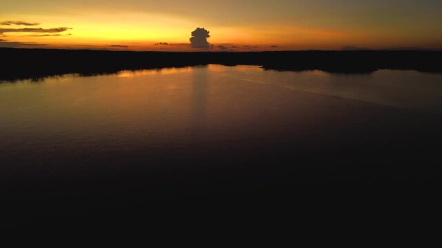 Orange Sunset Over Calm Amazon River in Ecuador with Dark Forest Silhouette, Water Reflection and Remote Tropical Wilderness Landscape
