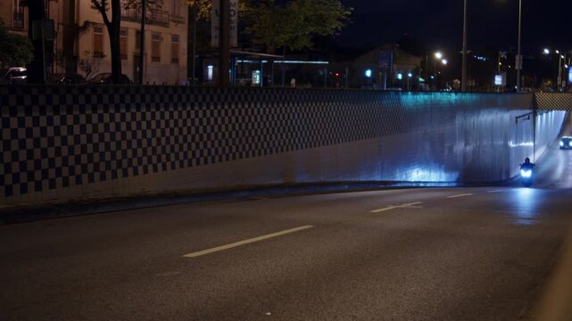 Cars driving out of an underpass tunnel at night. City traffic driving up a road tunnel at midnight. Late night streets filled with traffic. European late night traffic.