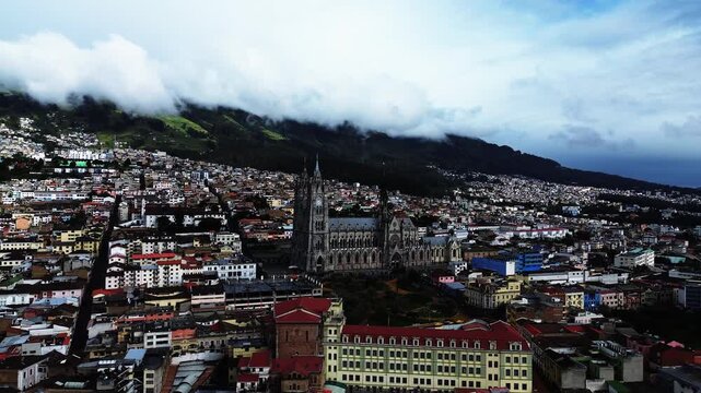 Aerial View of Quito Ecuador Historic Center by Day with Basilica, Dense City Buildings, Mountain Slopes and Cloudy Andean Skyline