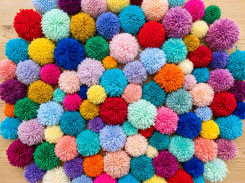 Many colorful soft yarn pom poms in a pile